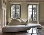 Modern living room with a unique cloud-shaped sofa and large windows.