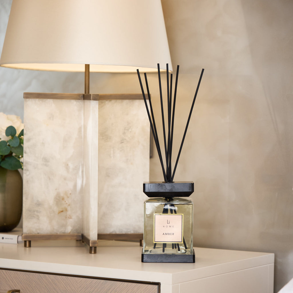 Decorative diffuser on a nightstand with a lamp in the background