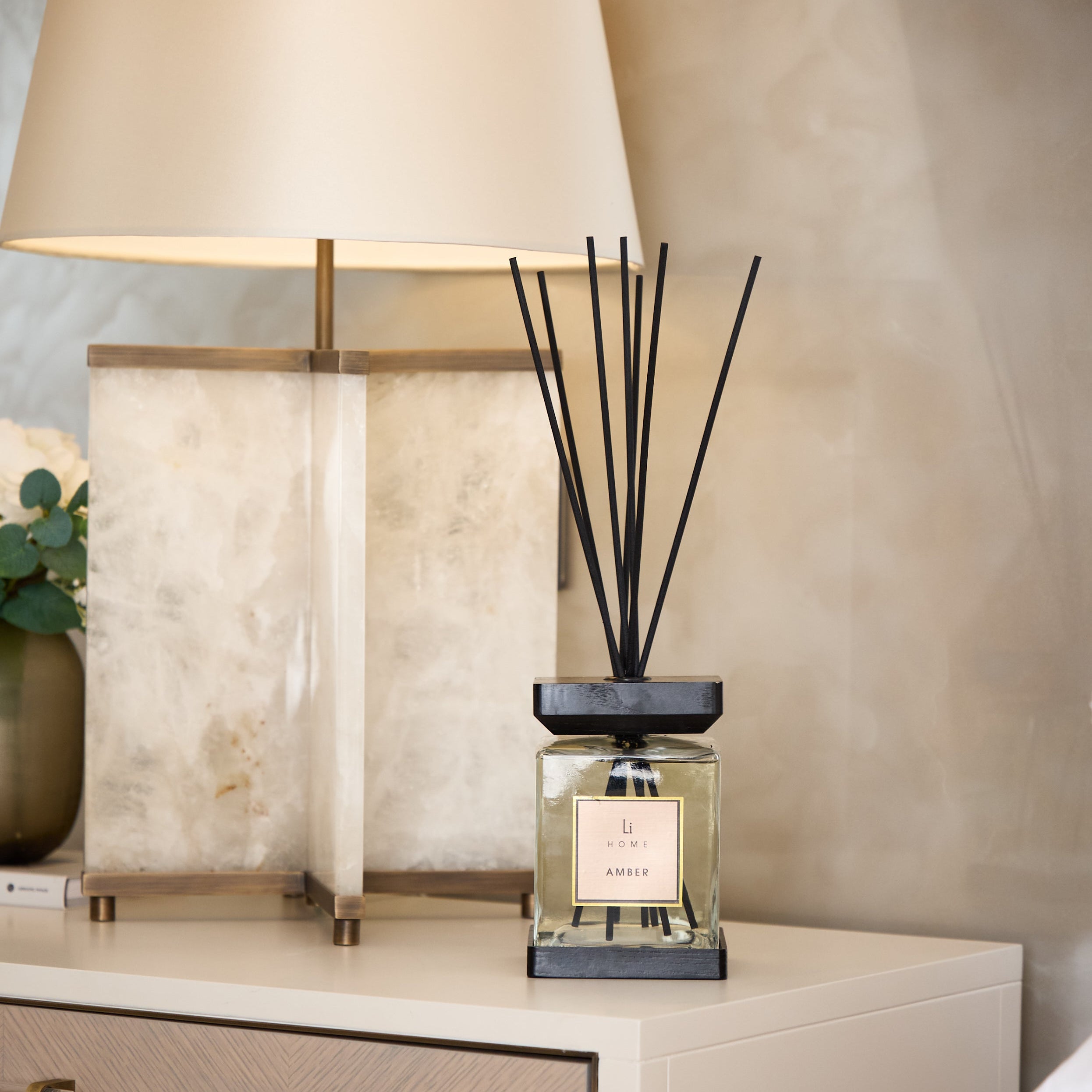 Decorative diffuser on a nightstand with a lamp in the background