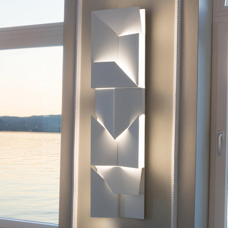 Modern wall-mounted light fixture with geometric design on a neutral wall.