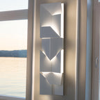 Modern wall-mounted light fixture on a neutral wall with a window in the background