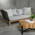 Outdoor furniture set with a sofa and coffee table against a gray wall.