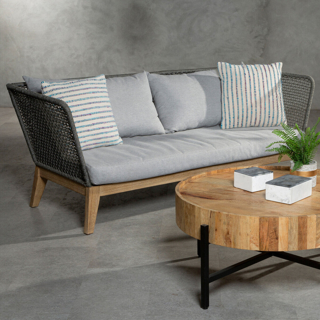 Gray sofa with striped cushions and a wooden coffee table on a concrete floor.