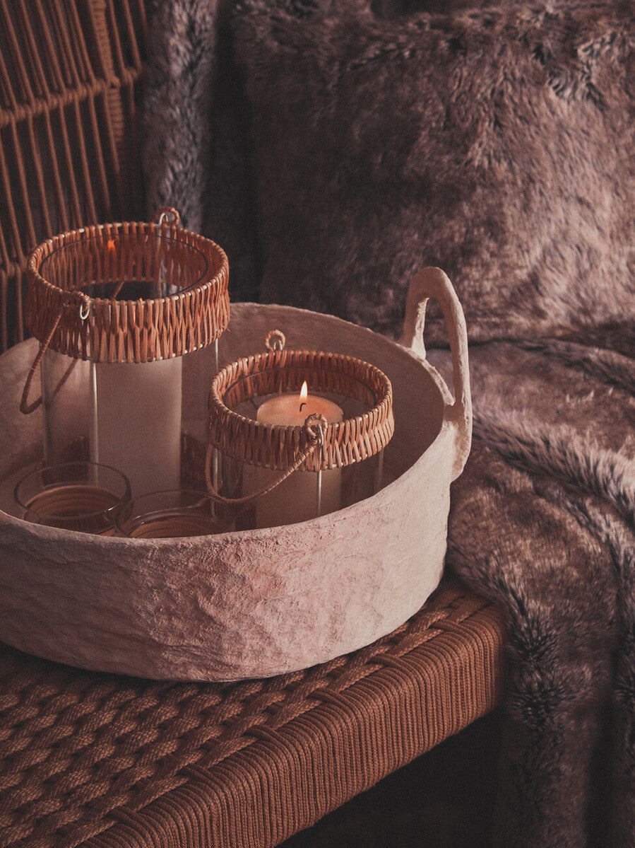 Candle in a decorative stone holder with wicker basket on a textured surface