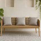 Wooden bench with gray cushions in a room with a light-colored wall and patterned rug.