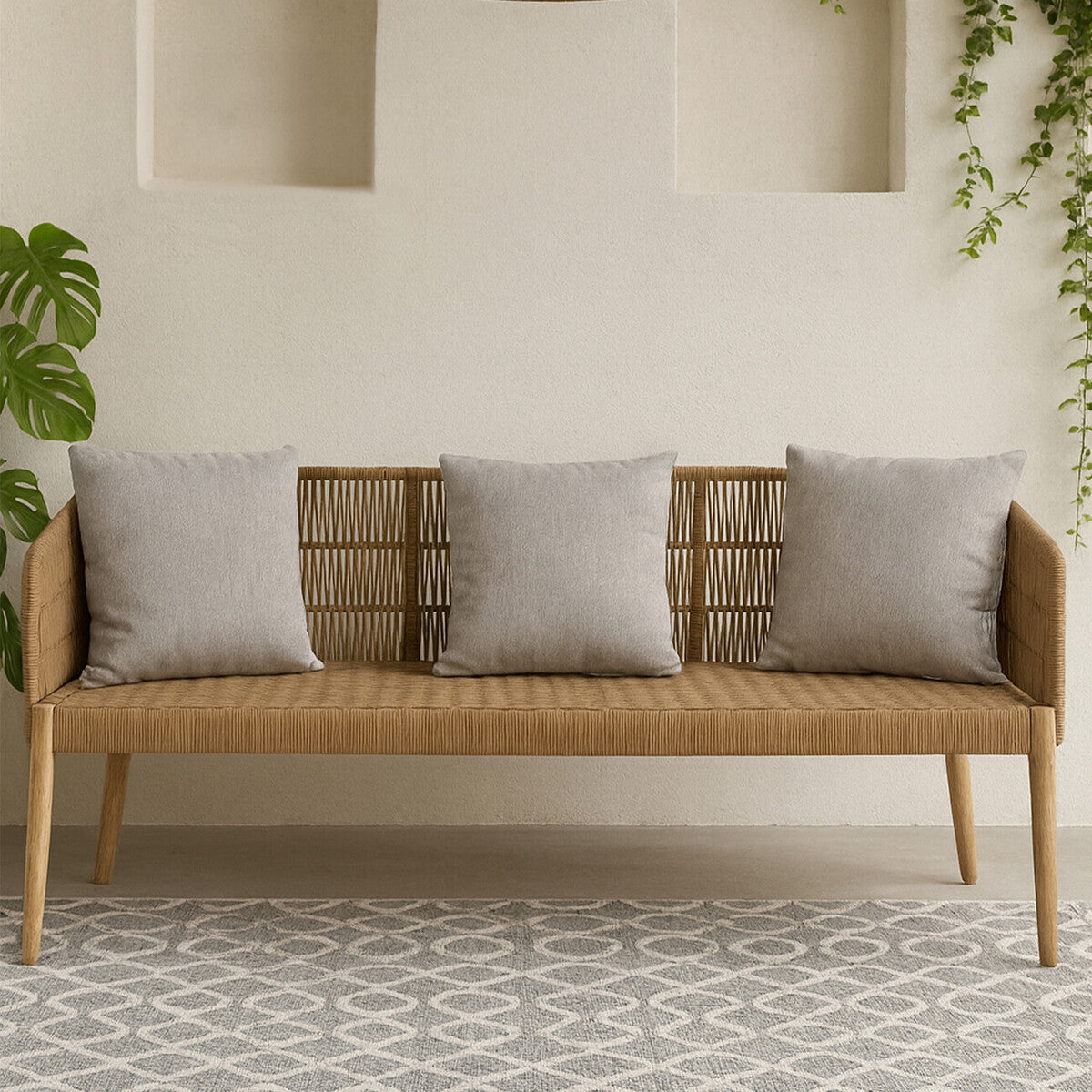 Wooden bench with gray cushions in a room with a light-colored wall and patterned rug.