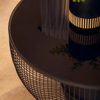 Round black metal coffee table with a textured surface on a beige floor.