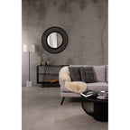 Modern living room with a gray sofa, round mirror, and decorative items.