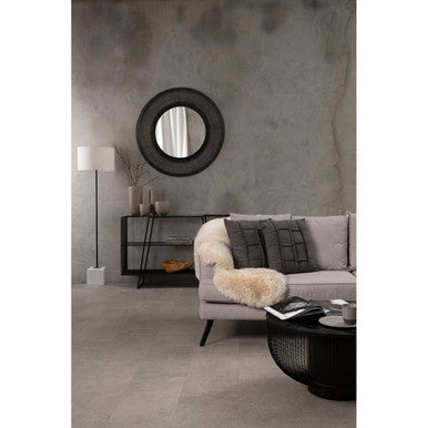 Modern living room with a gray sofa, round mirror, and decorative items.