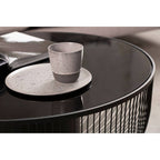 Gray ceramic cup on a round black table with a white background