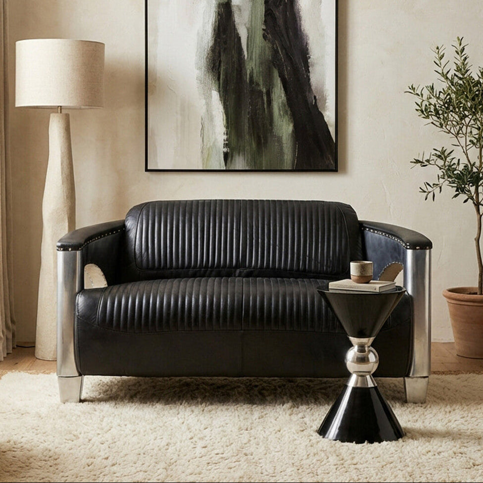 Modern living room with a black leather sofa, side table, and abstract art on the wall.