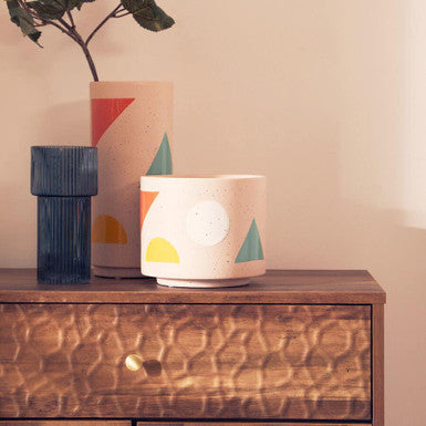Three ceramic pots with abstract designs on a wooden surface.