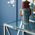 Glass vase on a clear glass table with a blue wall background