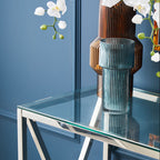 Glass vase on a clear glass table with a blue wall background