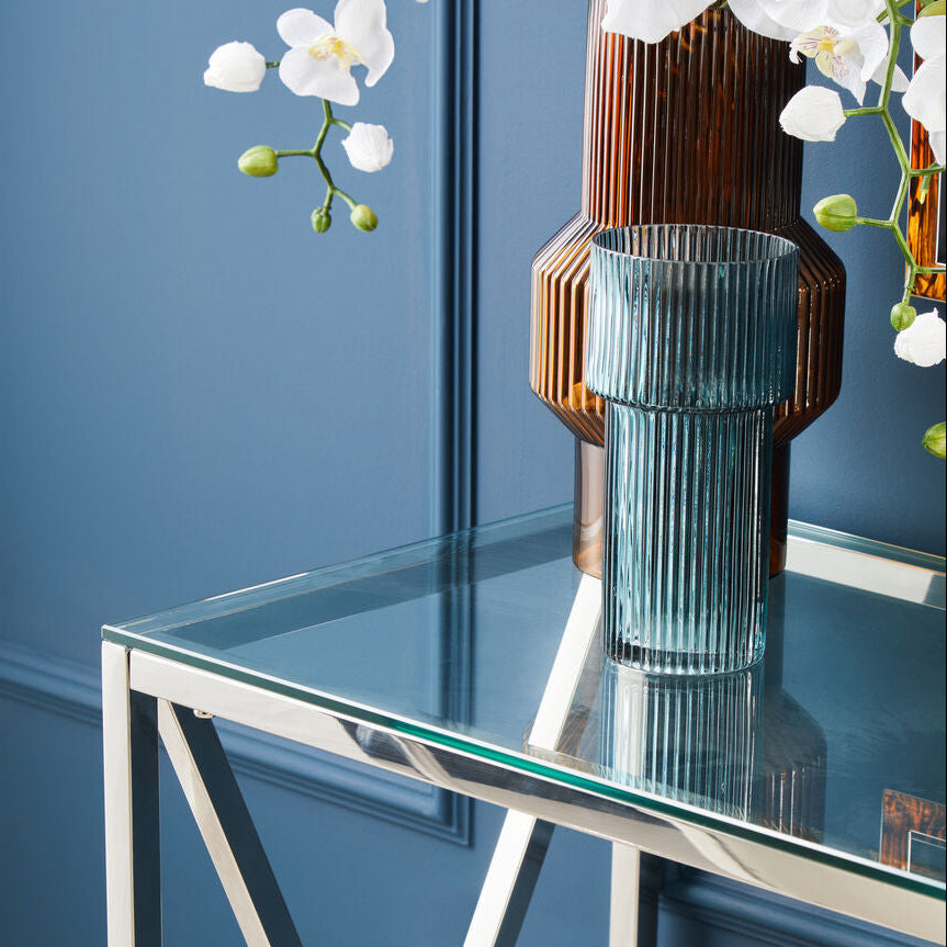 Glass vase on a clear glass table with a blue wall background