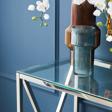 Glass table with a vase and flowers against a blue wall