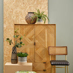Woven wooden cabinet with decorative items against a light green wall