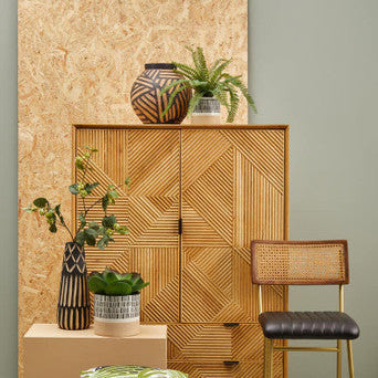 Woven wooden cabinet with decorative items against a light green wall