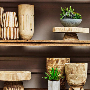 Wooden vases and planters on a shelf against a neutral background