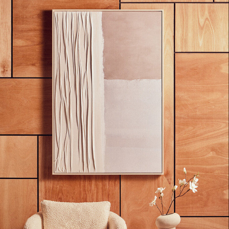 Abstract painting on a wooden wall with a textured chair and vase in the foreground.