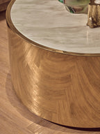 Round wooden coffee table with marble top on a wooden floor.