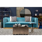 Modern living room with a blue sofa, coffee table, and decorative pillows against a purple wall.