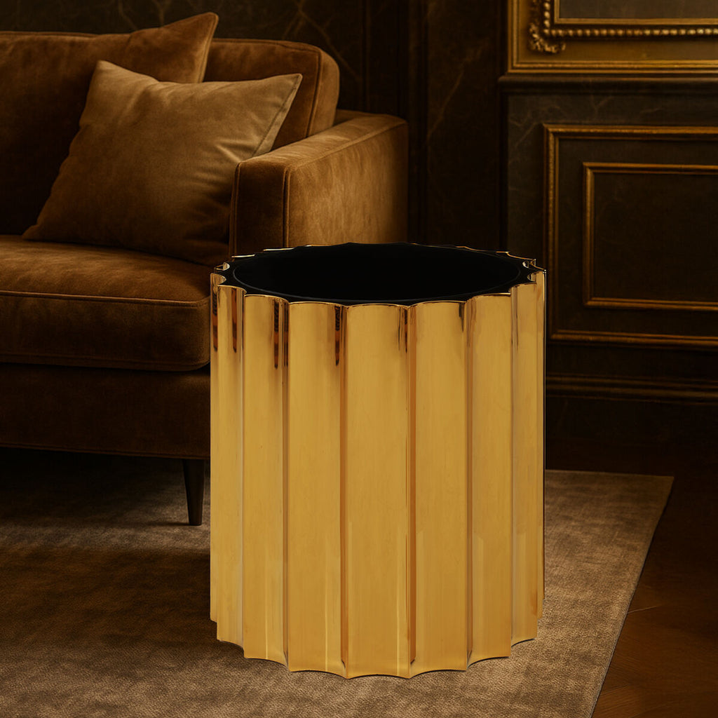 Gold side table with black top in a luxurious room with brown sofa and decorative wall.