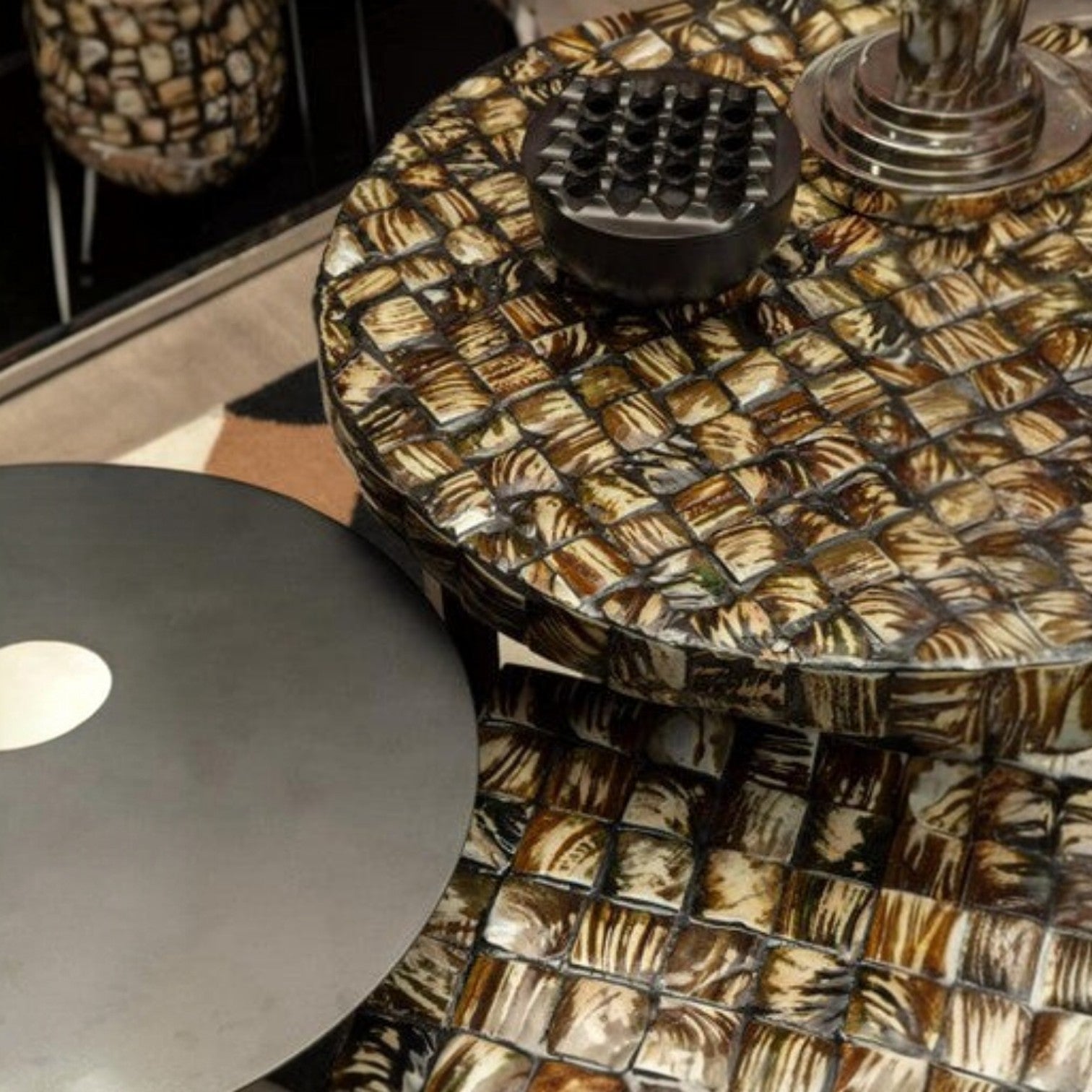 Round table with a patterned top and metallic base in an indoor setting