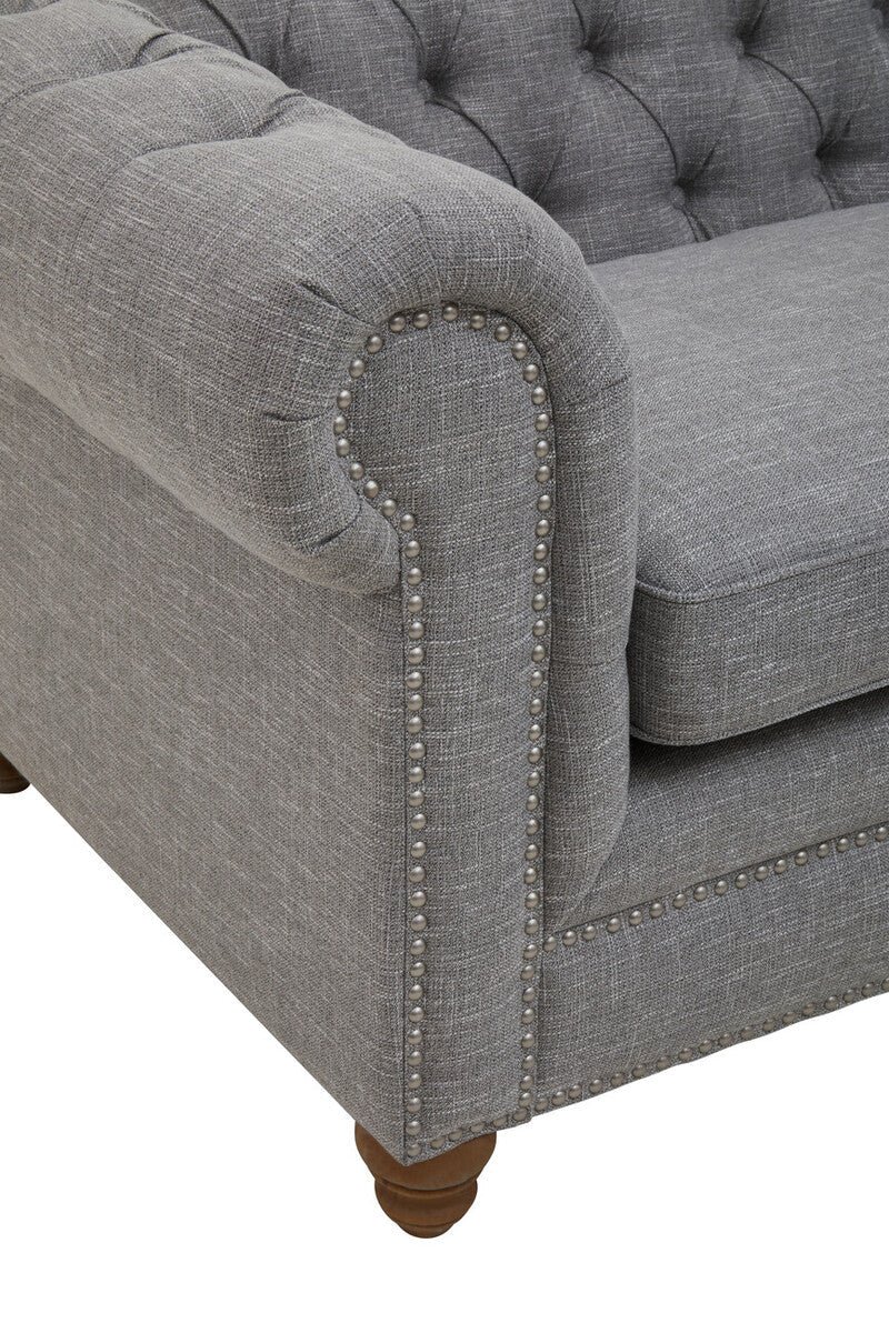 Gray tufted sofa with nailhead trim on a white background