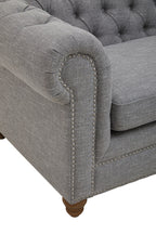 Gray tufted sofa with nailhead trim on a white background