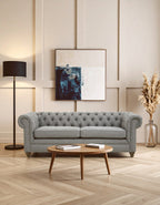 Gray tufted sofa in a living room with a wooden coffee table, lamp, and abstract painting on the wall.