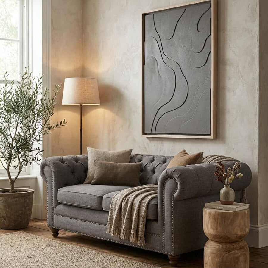 Living room with a gray sofa, lamp, and abstract painting on a neutral wall.