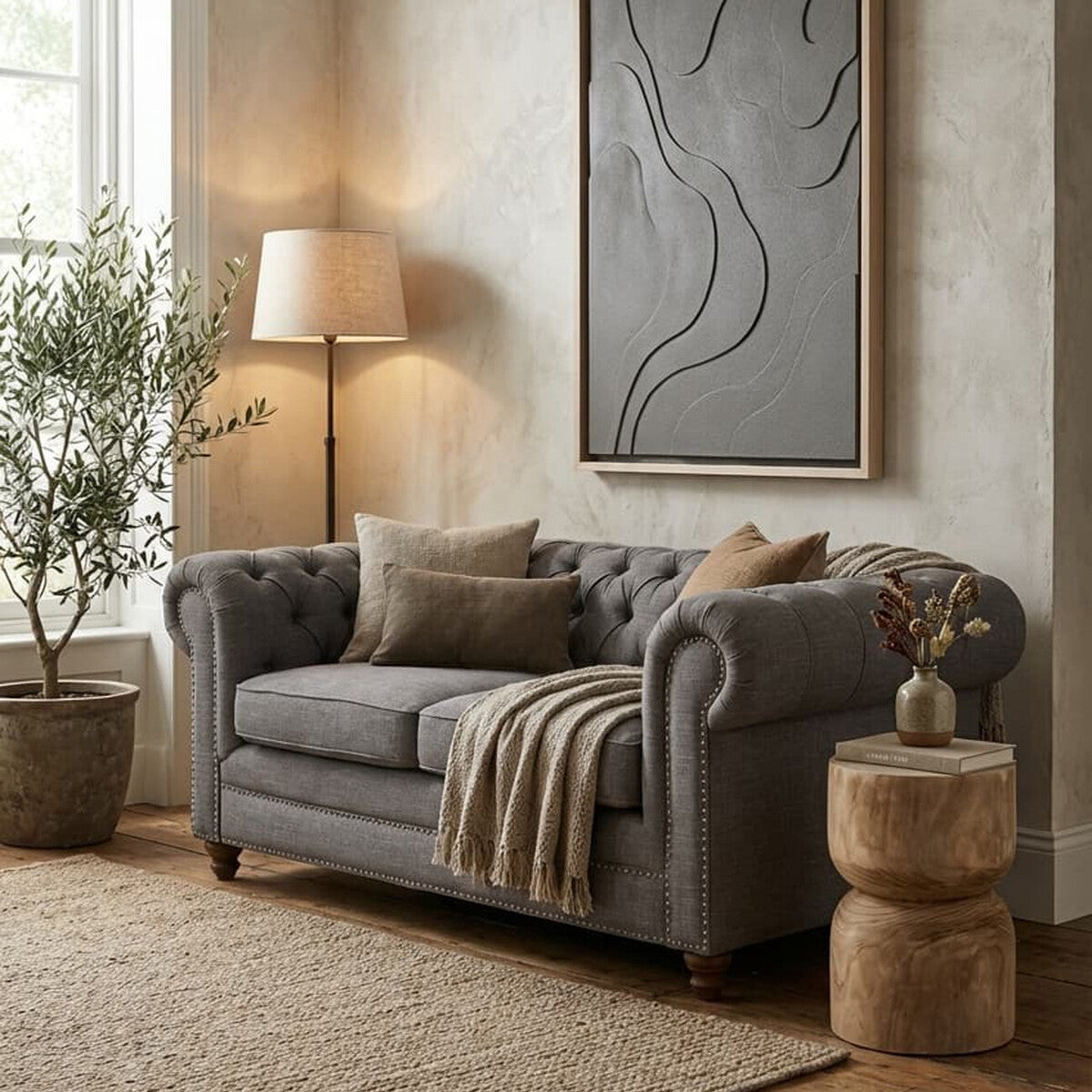 Gray sofa in a living room with a lamp, plant, and abstract art on the wall.