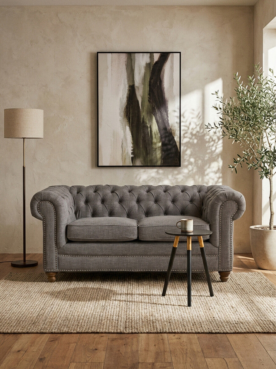 Gray tufted sofa in a living room with abstract art and decor