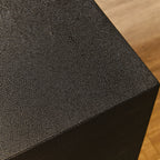 Black textured cube on a wooden surface
