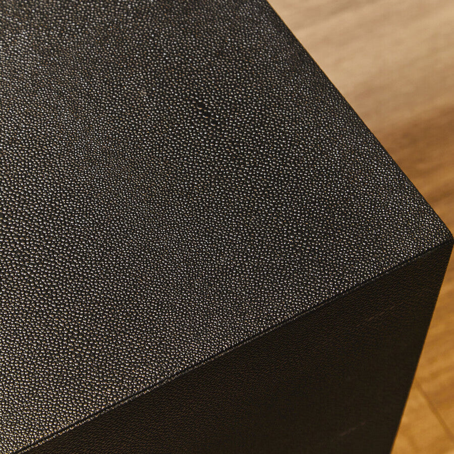 Black textured cube on a wooden surface