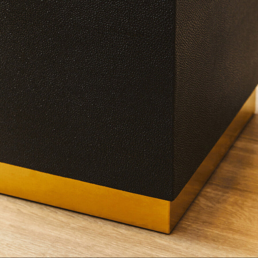 Close-up of a black textured surface with a gold base on a wooden floor.