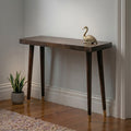 Wooden console table with a gold swan ornament against a plain wall.