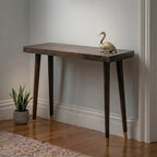 Wooden console table with a gold swan ornament against a plain wall.