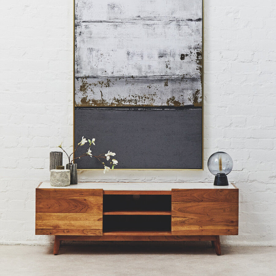 Wooden entertainment console with decorative items against a white brick wall.