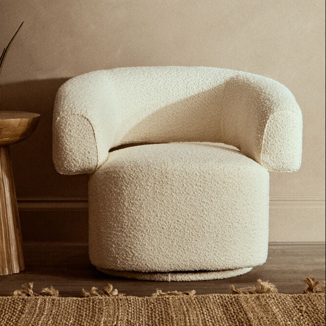 Beige textured armchair in a room with wooden floor and wall.