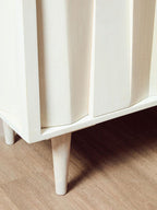 White cabinet with wooden legs on a wooden floor