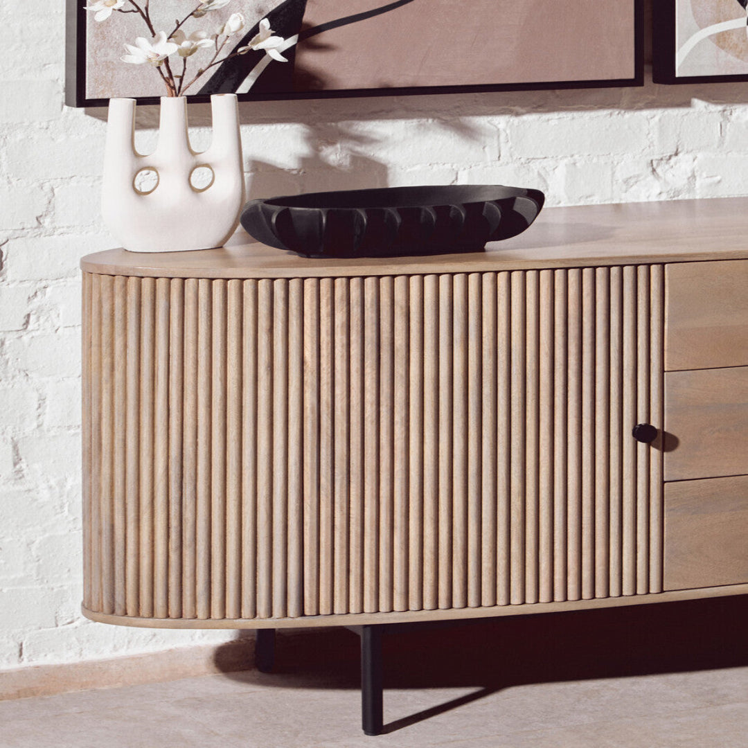 Wooden sideboard with decorative items against a white brick wall