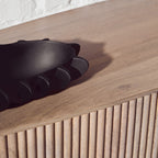 Black glove on a wooden surface with a white wall background