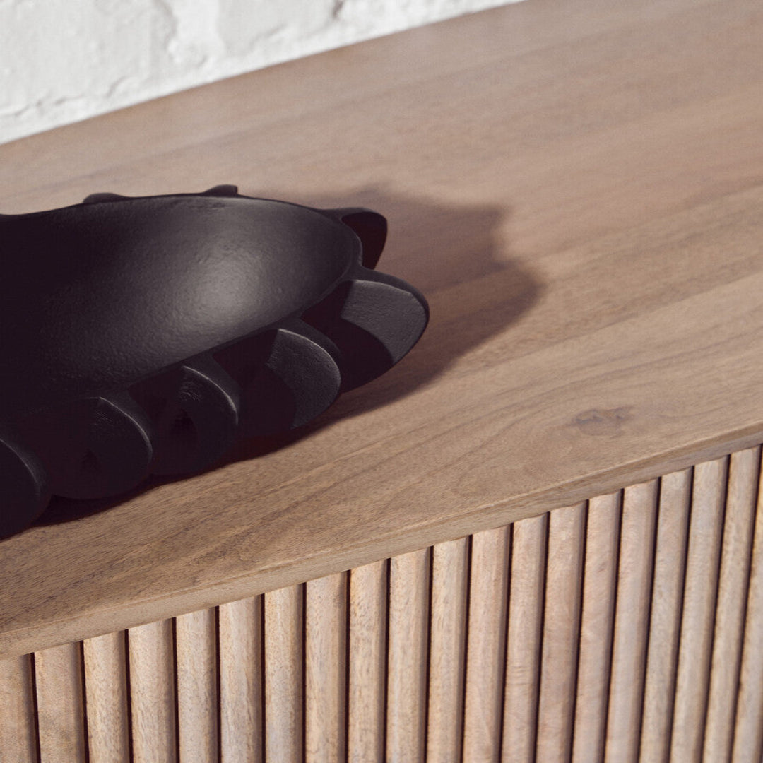 Black glove on a wooden surface with a white wall background