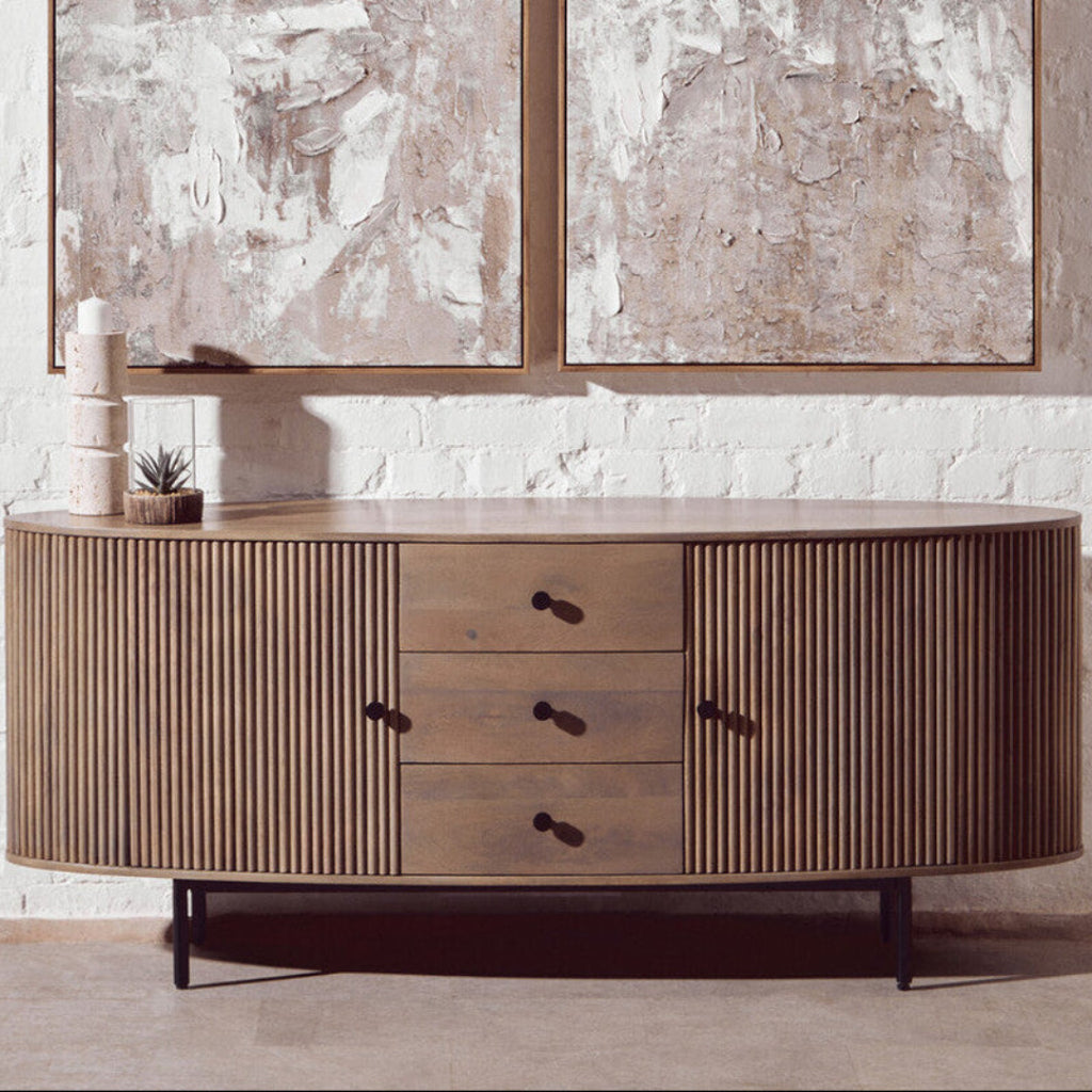 Wooden sideboard with drawers against a textured wall with abstract art.