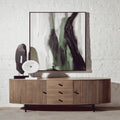Wooden sideboard with abstract art and decorative items against a white brick wall.