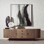 Wooden sideboard with abstract art and decorative items against a white brick wall.