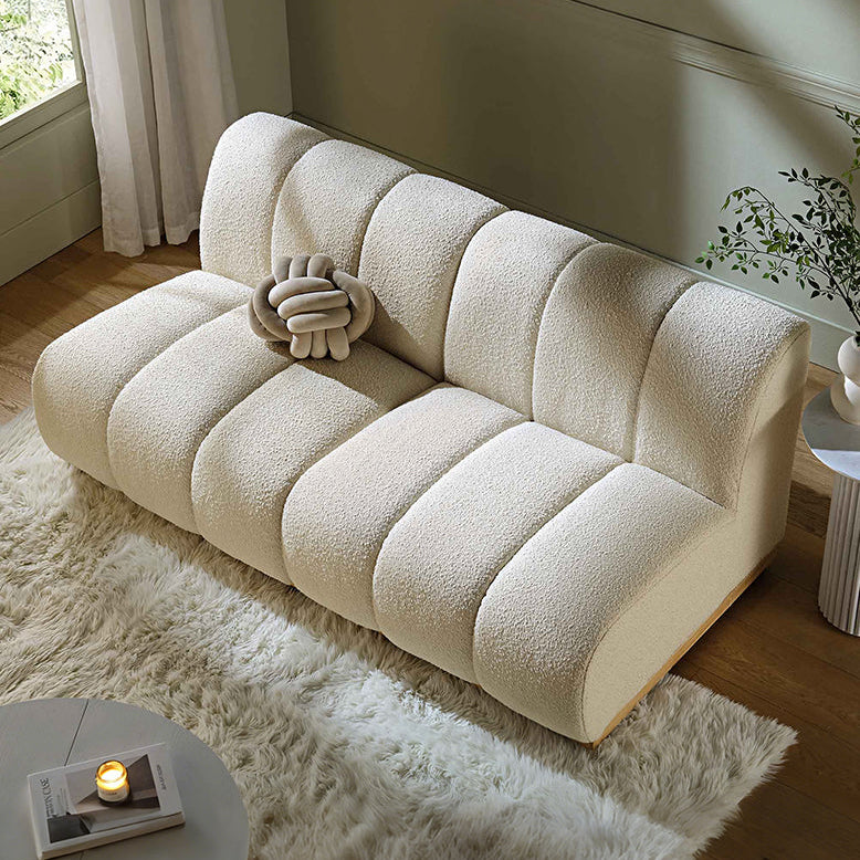 Beige sofa in a living room setting with a small table and plant.
