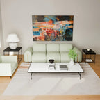 A modern living room setup featuring a light sage green three-seater sofa, a matching armchair, a white coffee table with black legs, black side tables, and a large colorful abstract painting on the wall.